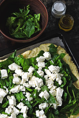 Cooking feta spinach pizza. Keto pizza. Raw feta spinach pizza on a sheet for baking. Flat lay.