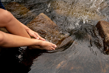 Woman sitting on a rug washed legs in the stream happy.