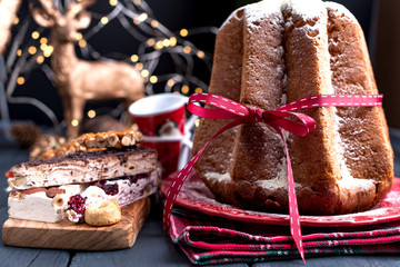 Italian Pandoro Christmas Cake with Lemon Cream. Decor and sweets for Christmas. A bokeh from the garlands and a black background. Winter holiday.