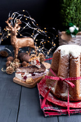 Italian Pandoro Christmas Cake with Lemon Cream. Decor and sweets for Christmas. A bokeh from the garlands and a black background. Winter holiday.