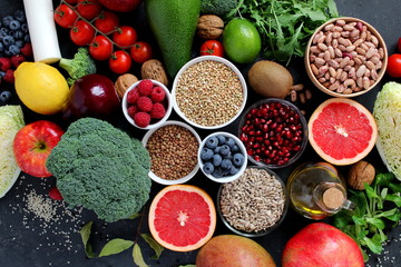 Healthy food concept. Vegetarian and vegan food: vegetables, fruits, legumes, leaf vegetables on dark background. Top view.