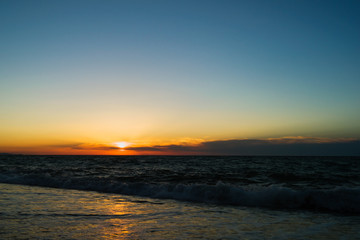 Sunset on the sea. Evening coast of the ocean. Small waves Clouds on the horizon.