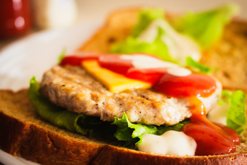 Hamburger made from whole wheat sliced bread, cheese, lettuce and topped with ketchup and slald dressing