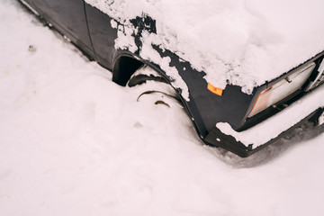 a car's front part buried in snow after a blizzard. Car covered with snow after big snowstorm.