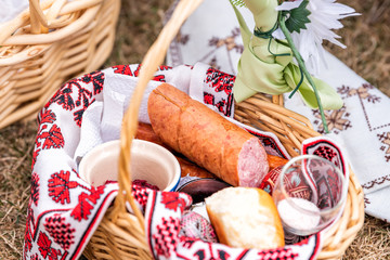 Russian Orthodox Easter blessing wicker straw basket with sausage meat, nobody on grass ground outside at church, flowers - Powered by Adobe