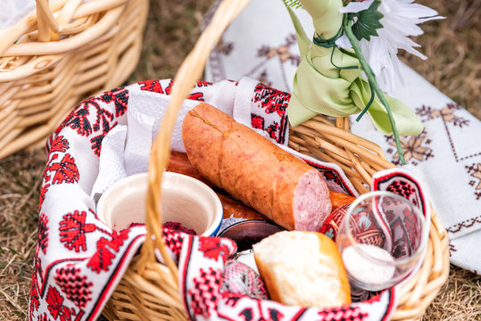 Russian Orthodox Easter blessing wicker straw basket with sausage meat, nobody on grass ground outside at church, flowers