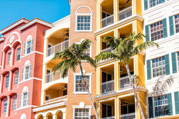 Condos, condominiums colorful, orange yellow multicolored buildings facade exterior with windows, palm trees, real estate property in Spain - obrazy, fototapety, plakaty