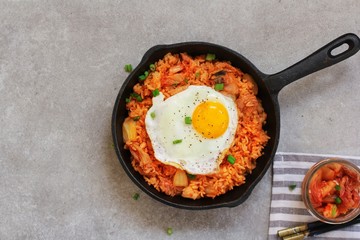Homemade Kimchi Fried rice topped with fried egg on skillet, overhead view - obrazy, fototapety, plakaty