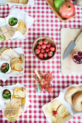 Top view background of rustic table with food set for picnic or summer party, focus on ripe delicious strawberries in wooden bowl and lemonade drinks, copy space