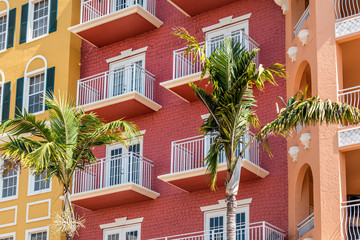 Florida condo, condominium colorful, red multicolored buildings facade exterior with windows, palm...
