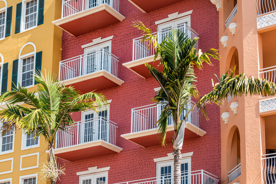 Florida condo, condominium colorful, red multicolored buildings facade exterior with windows, palm trees, real estate property in Spain