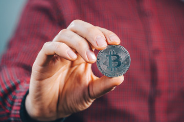 Fototapeta na wymiar Bitcoin. Close up cropped shot of smiling man holding bitcoin in hand. Business, finance, chrypto currency concept.