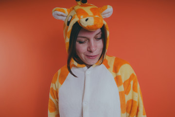pajamas in the form of a giraffe. emotional portrait of a girl on an orange background. crazy and...