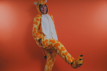 pajamas in the form of a giraffe. emotional portrait of a girl on an orange background. crazy and...