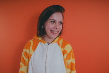 pajamas in the form of a giraffe. emotional portrait of a girl on an orange background. crazy and...