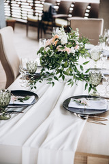 Wedding table serving. Festive decor. Wedding decorated  with flowers table with cutlery for the guests. Beautiful decor with pastel roses and greenery