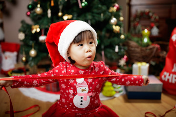 toddler baby girl wearing santa claus costume play in front of christmas tree