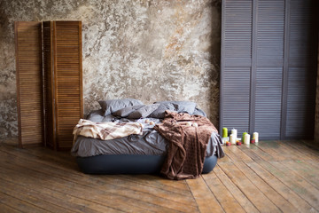 loft the room with a gray bed on a wooden floor with gray walls, candles and wooden scenery