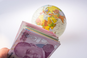 Turkish Lira banknotes by the side of a model globe