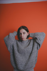 Young girl in warm grey sweater posing on orange background, woman with short haircut in knitted...