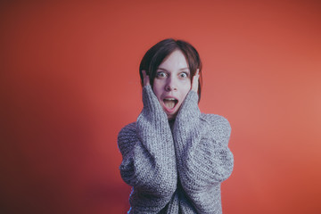 Young girl in warm grey sweater posing on orange background, woman with short haircut in knitted...
