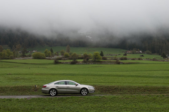 Curon Venosta, Bolcano / Italy - 2 May 2018: Passat CC Car Shot In Profile Staying On The Road With Moutains Hidden By The Fog On The Background