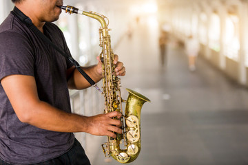 Fototapeta na wymiar A street musician plays the saxophone with blurry people