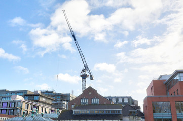 A modern construction crane in a sunny winter day on the Avon wharf as seen from Castle Park in Bristol, United Kingdom