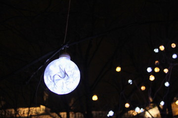Christmas decoration in the form of a glowing electric ball on a dark sky background.