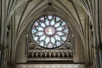 The main rose window under the pointed arch vault with colored stained glasses and Gothic decorations in the Bristol Cathedral, United Kingdom