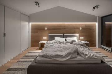 Stylish bedroom in modern style with light walls and luminous lamps