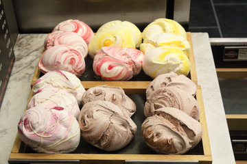 Many colors (white, brown, yellow) meringue sweets on two wooden trays in a backery shop in Bath, United Kingdom
