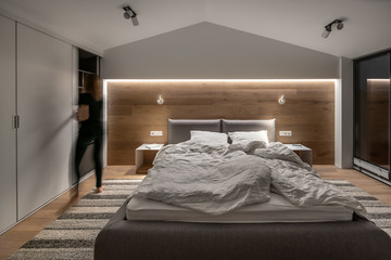 Stylish bedroom in modern style with light walls and luminous lamps