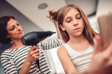 Mother drying hair to her daughter