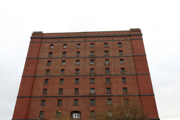 An abandoned old big industrial building made of red bricks with many periodically distributed windows in a cloudy day in Butterfly Junction, Bristol