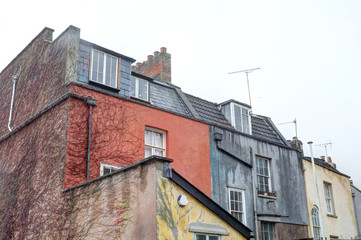 Fototapeta na wymiar Colored terrace houses with sash hung windows, black roofs and chimney stacks in a cloudy day in Bristol, United Kingdom