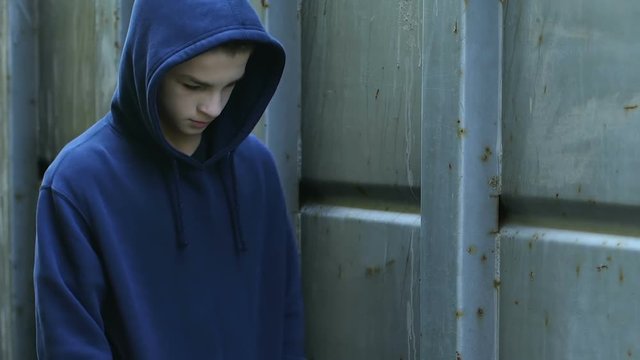 Upset lonely boy walking at school backyard, bored teenager skipping classes