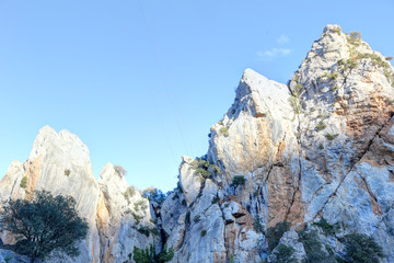 The Foz de Escalete breach on the high rocky escarpments due to water erosion next to La Peña lake, with trees on rocks, at sunset, in Aragon, Spain