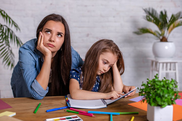 Mother becoming frustrated with daughter whilst doing homework sitting at the table at home in...