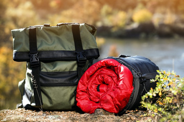 Backpack and sleeping bag on ground outdoors. Camping equipment
