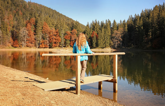 Woman enjoying view of autumn forest near lake