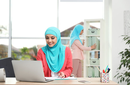 Modern Muslim women working in light office