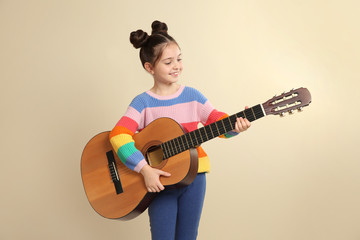 Obraz premium Cute little girl playing guitar on color background