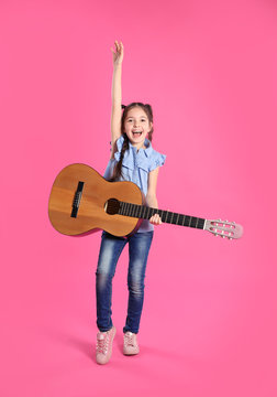 Cute little girl playing guitar on color background