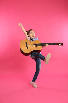 Cute little girl playing guitar on color background