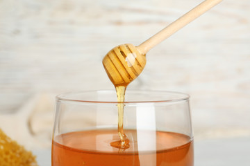 Sweet honey dripping from dipper into jar, closeup