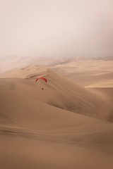 Fototapeta na wymiar paragliding over sand dunes in desert