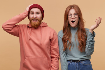 Omg! Horizontal shot of young male and female, have shocked, astonished facial expression, hold...