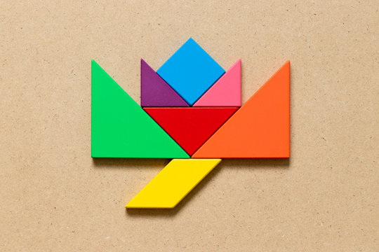 Color tangram puzzle in blooming flower shape on wood background