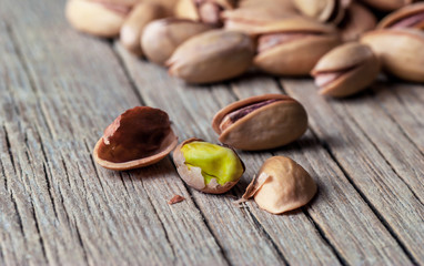Peeling Pistachio in nutshell on wooden rustic backdrop, composition of pistachios great for healthy and dietary nutrition. Concept of nuts